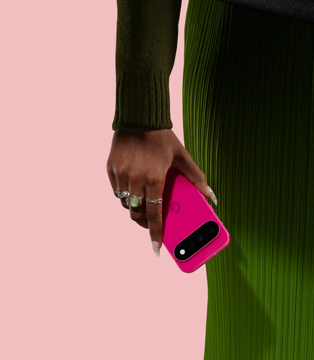 A hand holding a magenta Pixel against a green pleated skirt