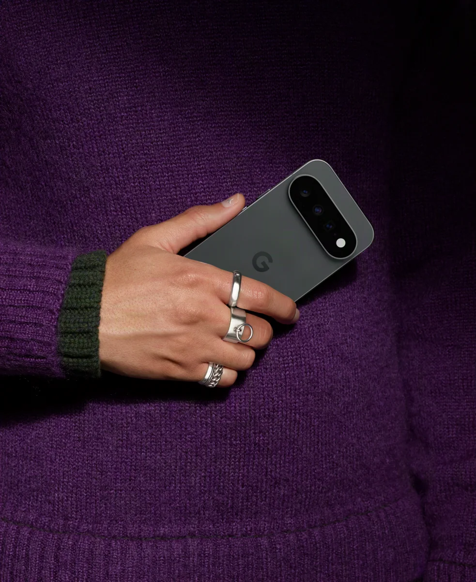 A hand holding an Obsidian Pixel against a purple knit sweater